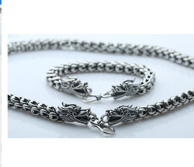 Silver chain necklace with dragon design on a white background