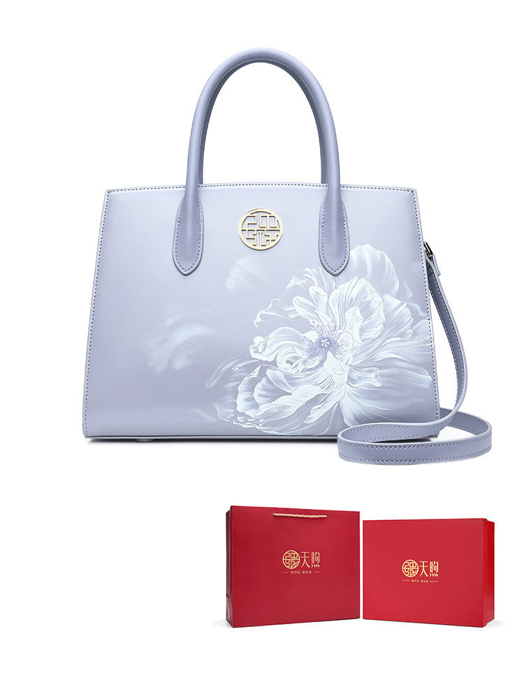 Light blue handbag with floral design and matching red boxes on a white background