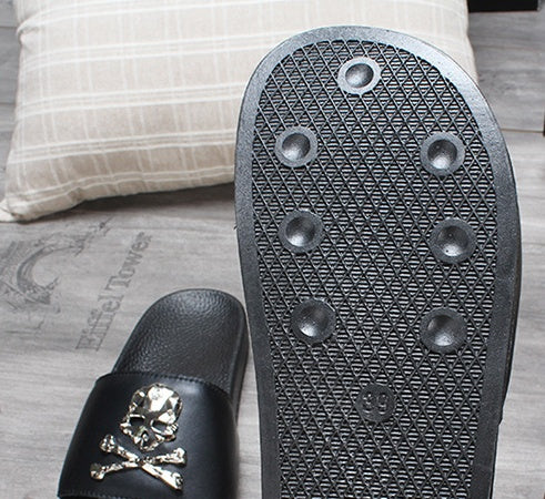 Black slide sandal with skull design on a textured surface