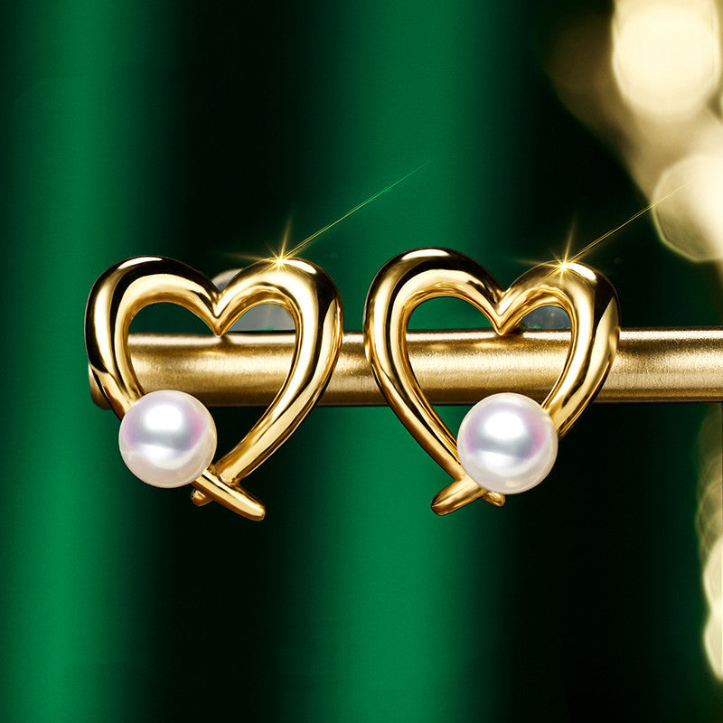 Gold heart-shaped earrings with pearls on a green background