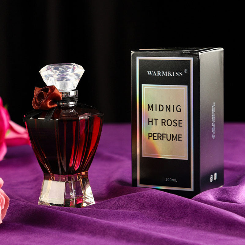 Perfume bottle and packaging with 'WARMKISS' branding on a purple fabric background
