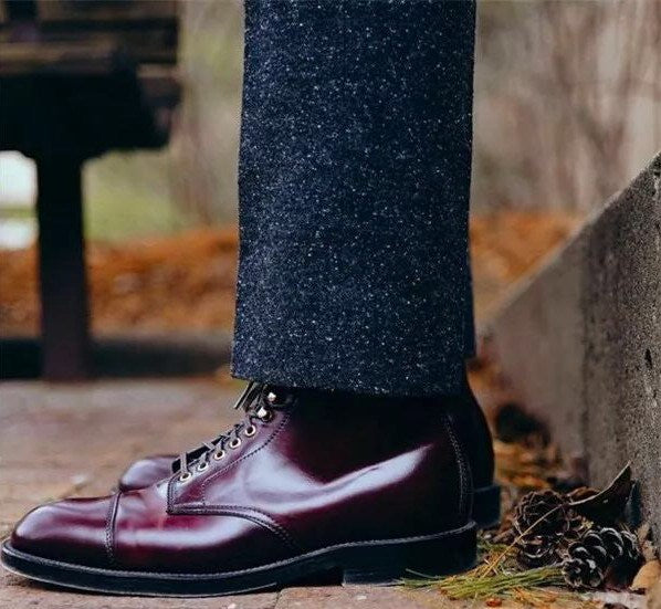 Close-up of a person wearing dark red leather shoes with a blurred outdoor background