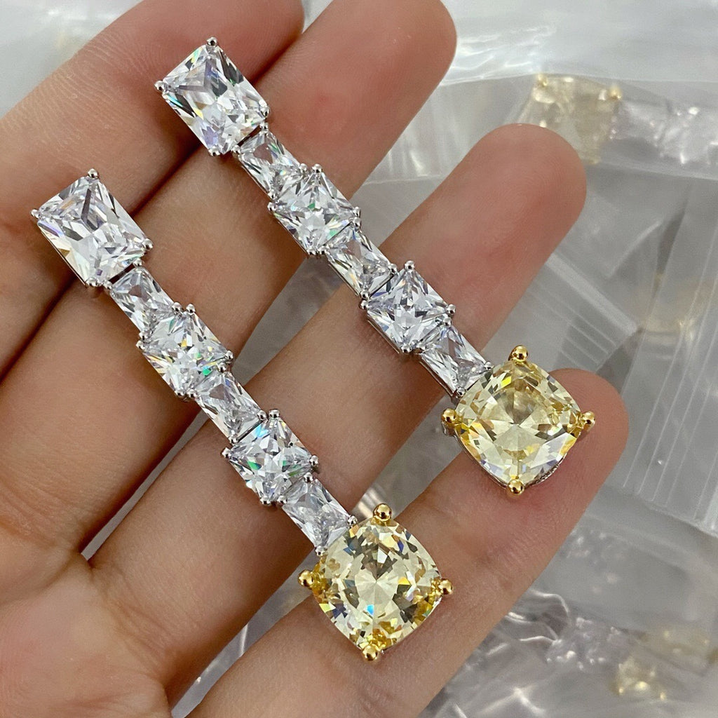 Diamond earrings held in a hand with a blurred background