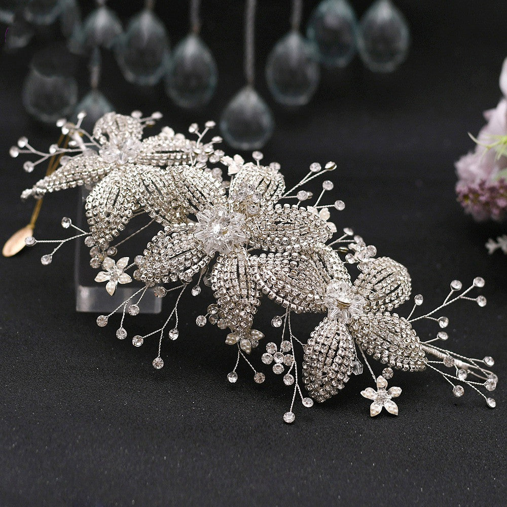 Silver floral hairpiece with intricate details on a dark background