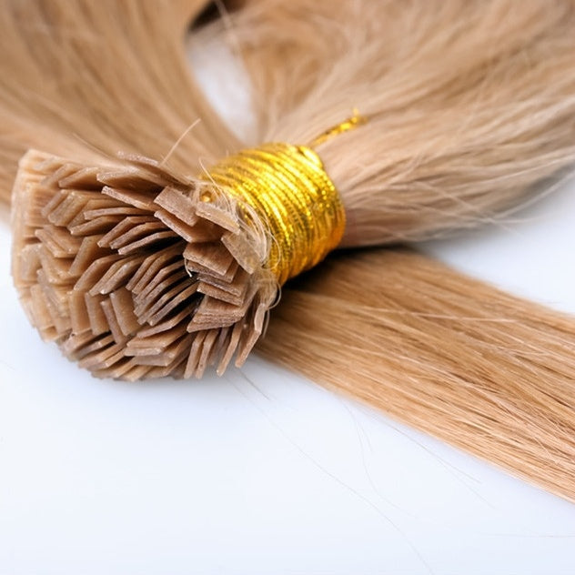 Blonde hair extensions with a gold tie on a white background