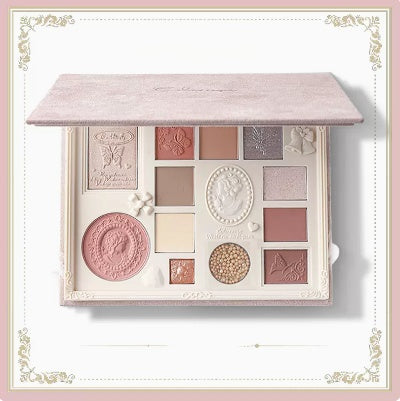 Makeup palette with various shades and decorative elements on a light pink background