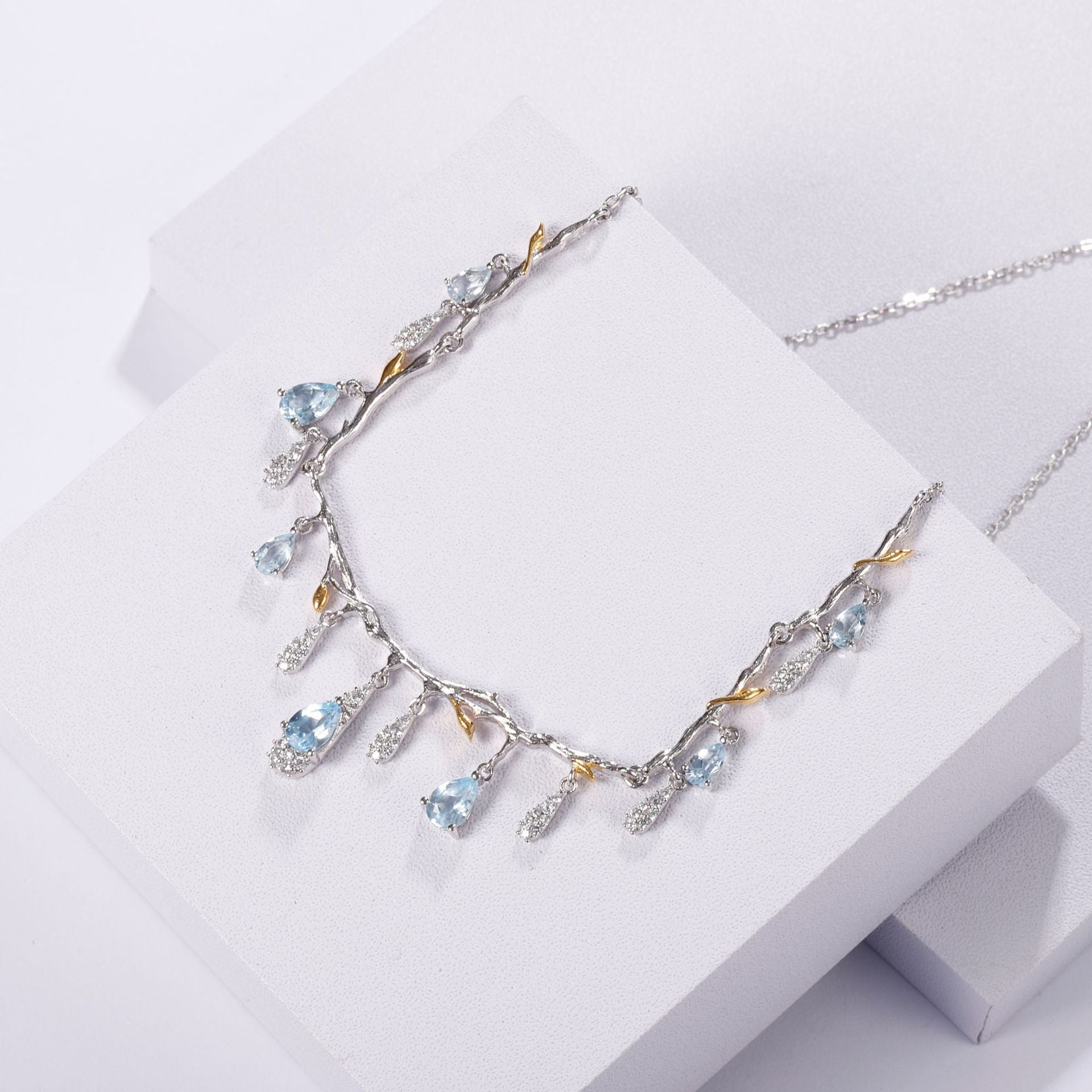 Silver necklace with blue gemstones on a white surface