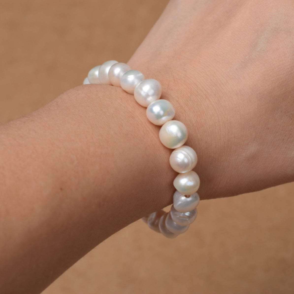 Pearl bracelet on a wrist against a neutral background