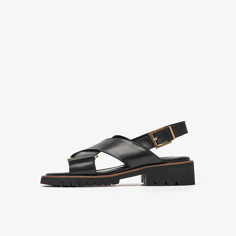 Black sandal with a gold buckle on a white background