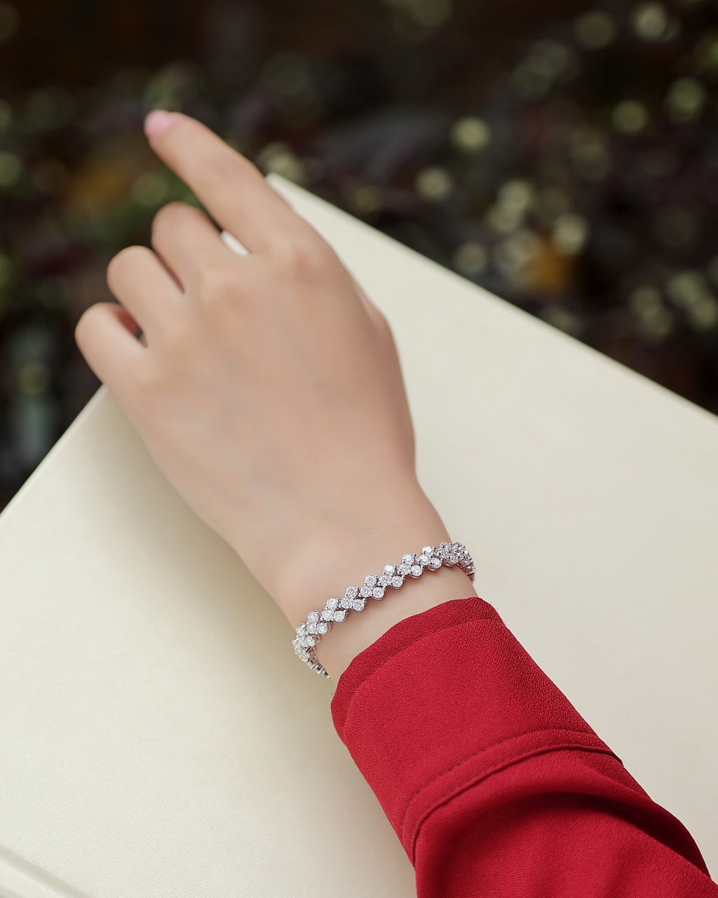 Hand wearing a silver bracelet on a blurred background