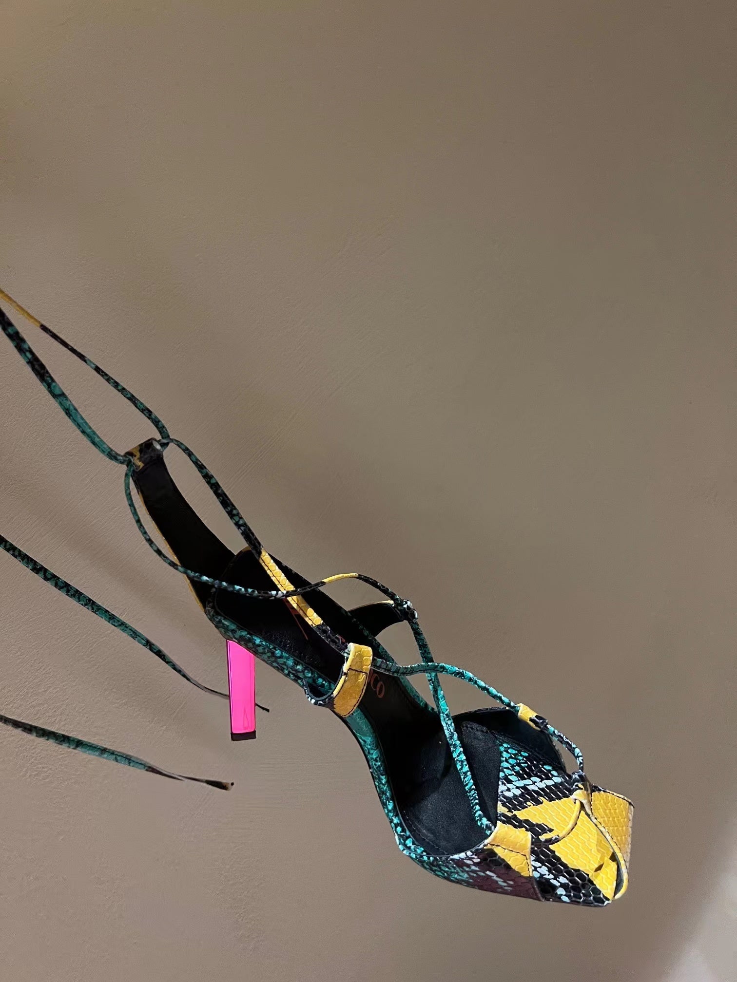 High-heeled shoe with colorful pattern on a neutral background