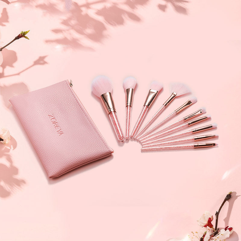 Set of makeup brushes with a pink case on a pink background