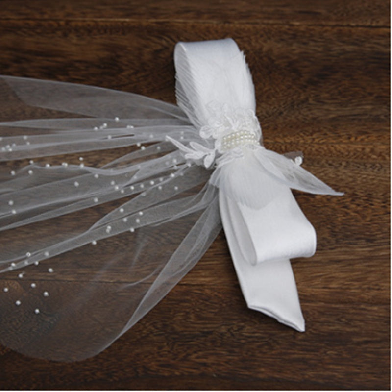 White decorative napkin with a sheer overlay and pearl accents on a wooden surface