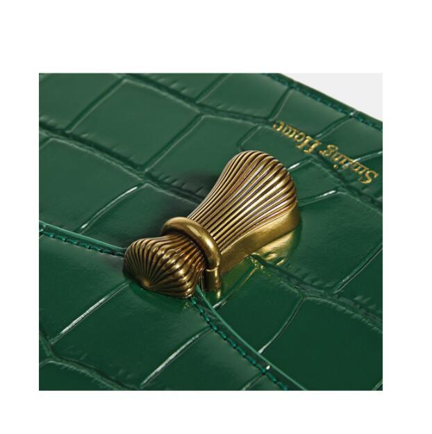 Green textured surface with a gold decorative element and 'Serge Lutens' branding.