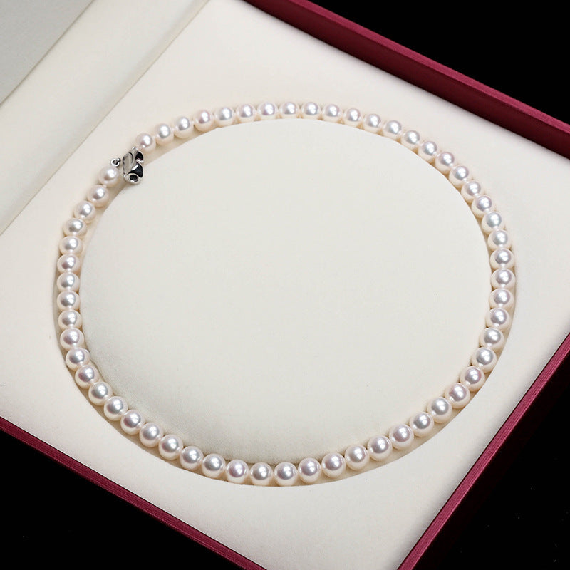 Pearl necklace on a white cushion with a red border