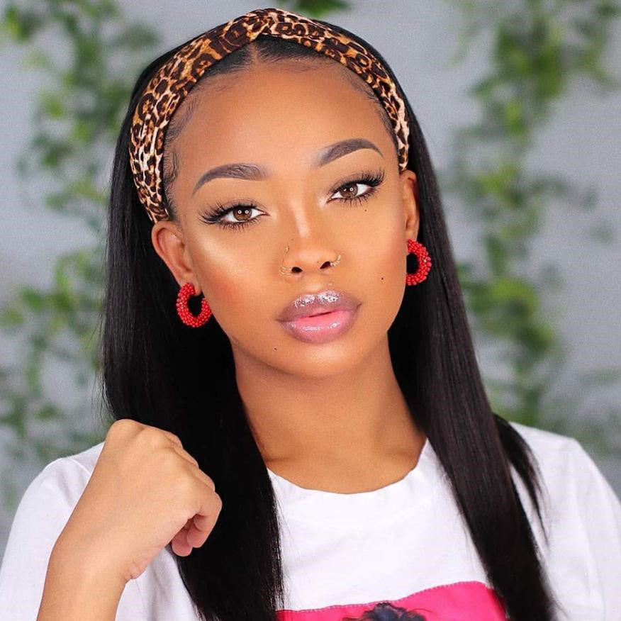 Woman with leopard print headband and red hoop earrings against a blurred green background