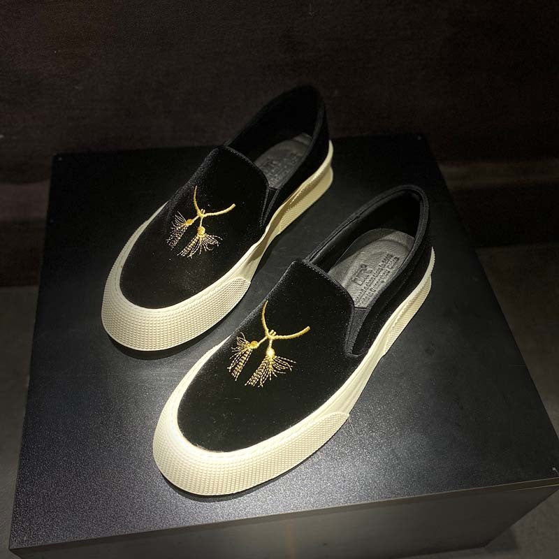 Black loafers with gold embroidery on a black box