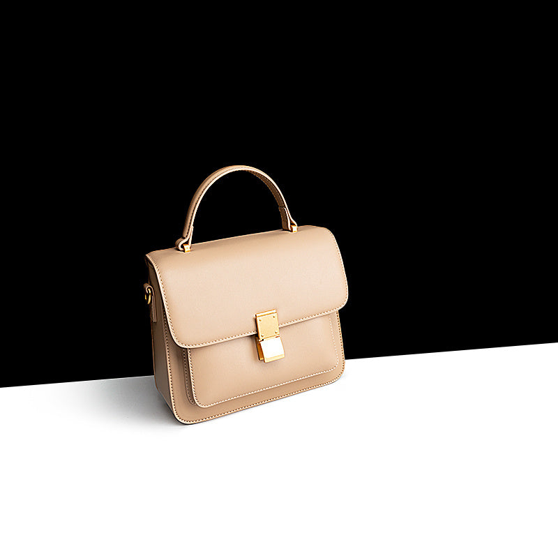Beige handbag with a gold clasp on a black and white background