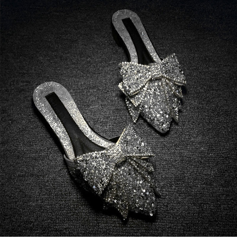 Pair of glittery shoes with bow details on a black background