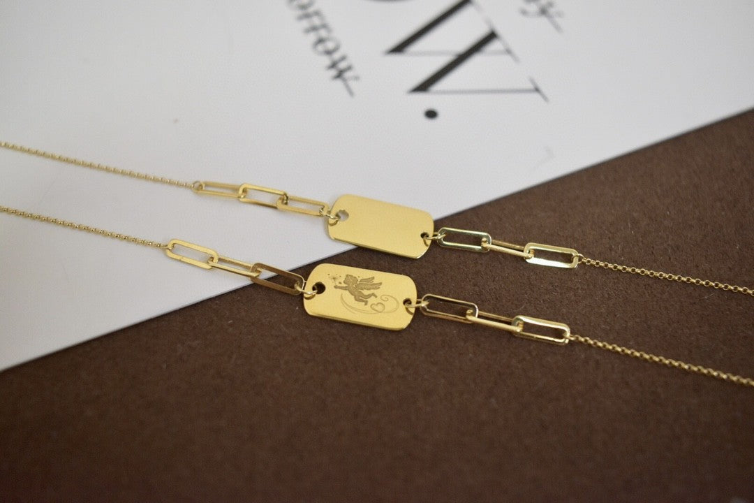 Gold chain with dog tags on a textured surface
