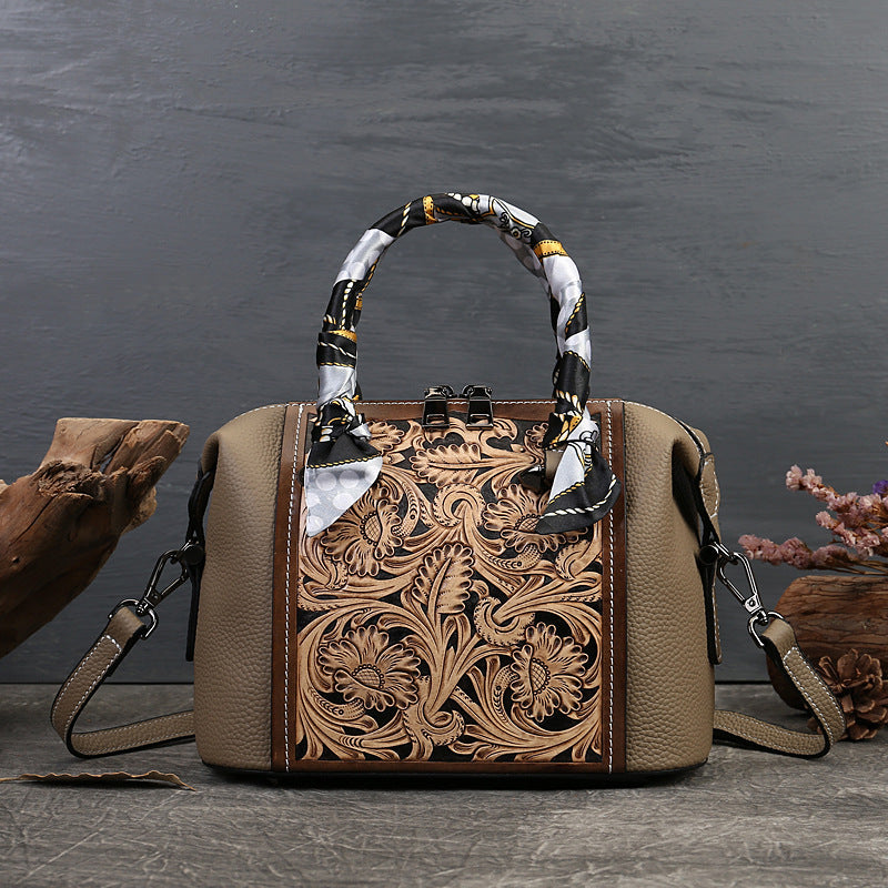 Brown leather handbag with intricate floral patterns on a dark background