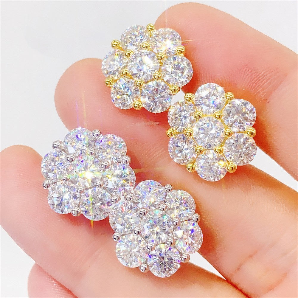 Gold and silver earrings held in a hand against a white background
