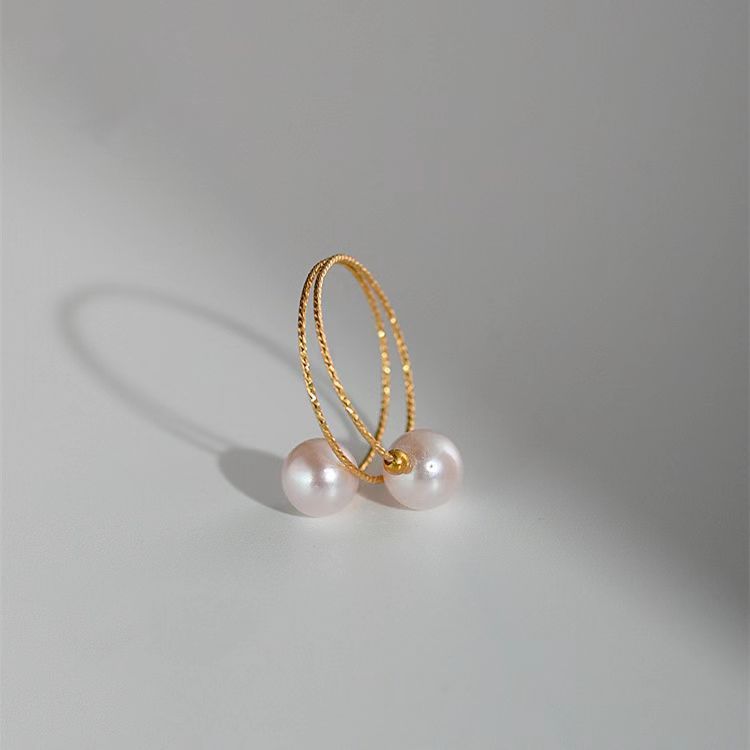 Gold hoop earring with two pearls on a gray background