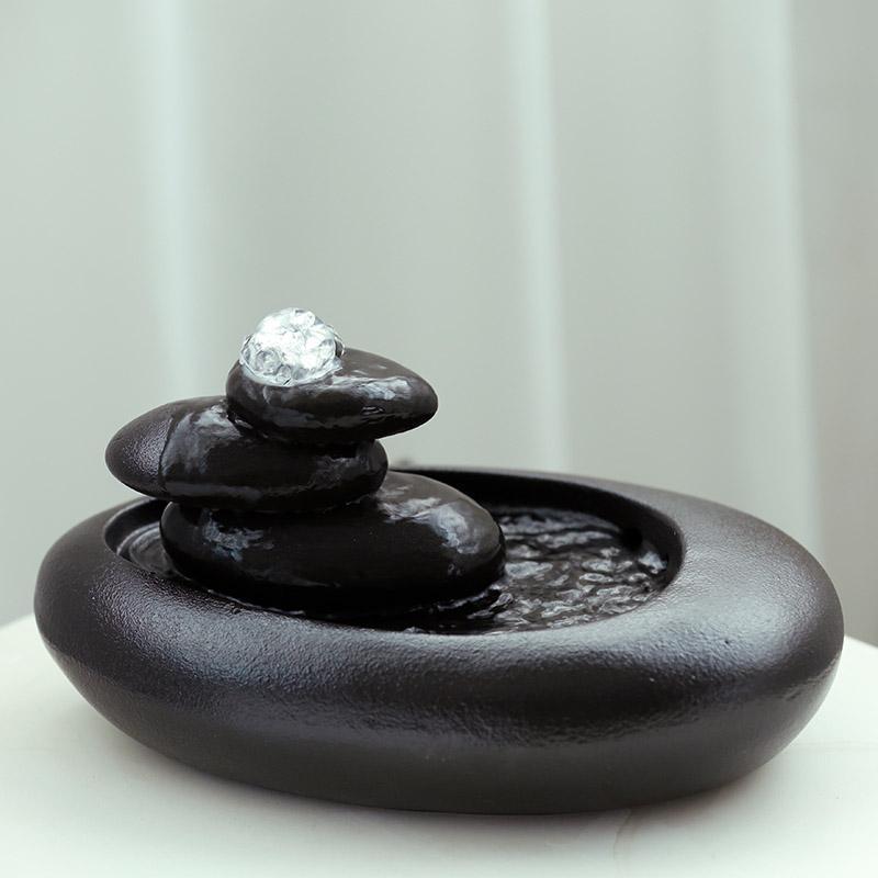 Decorative black stone water fountain on a white surface with a neutral background