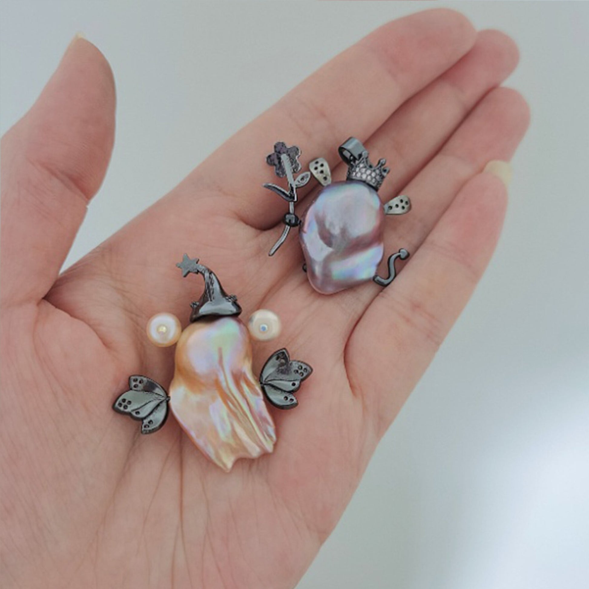 Hand holding various pearl and silver jewelry pieces on a plain background