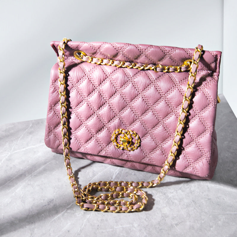 Pink quilted handbag with gold chain strap on a light gray background
