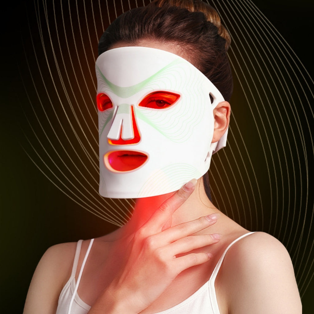 Woman wearing a LED face mask with red and green lights on a dark background