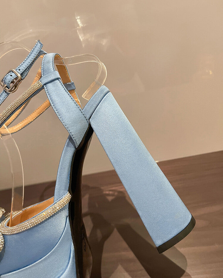 Light blue high-heeled shoes with gold accents on a reflective surface.
