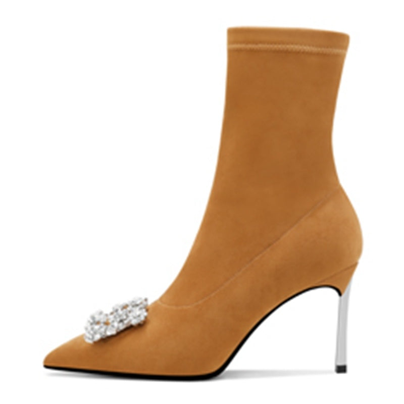 Tan suede ankle boot with a high heel and decorative brooch on a white background