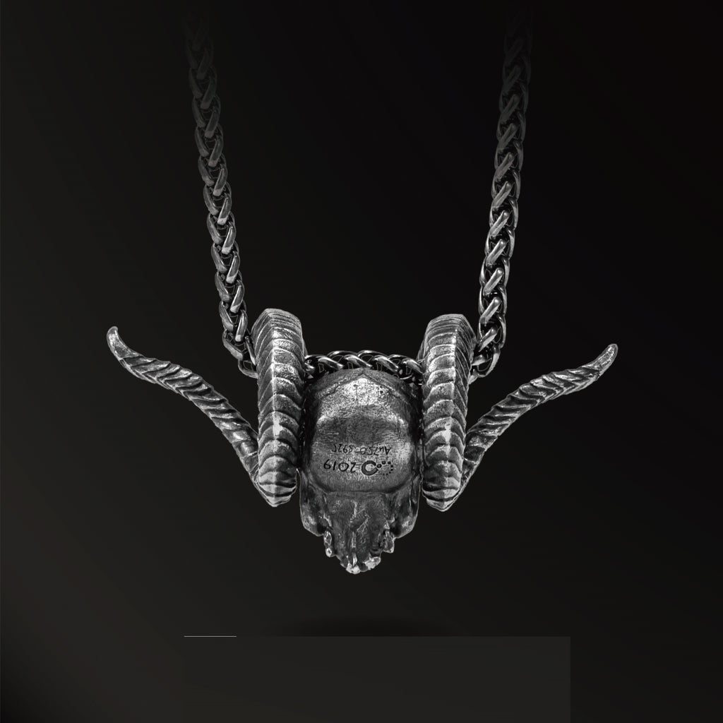 Silver ram head necklace on a black background