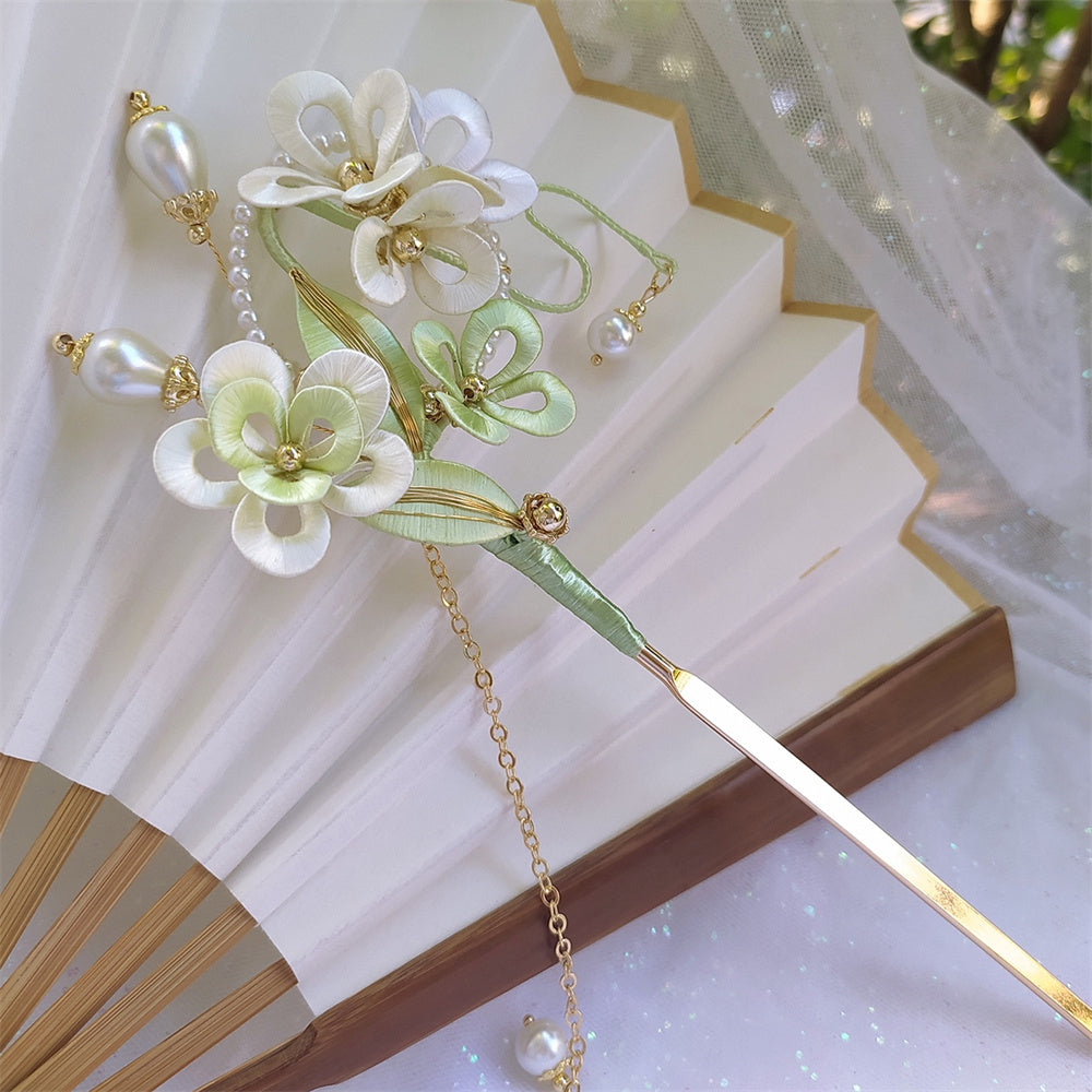 Decorative hairpin with floral design and pearls on a white background