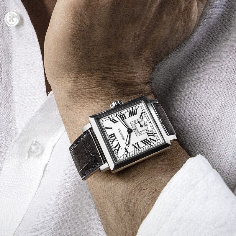 Luxury watch with a black strap on a person's wrist, wearing a white shirt.