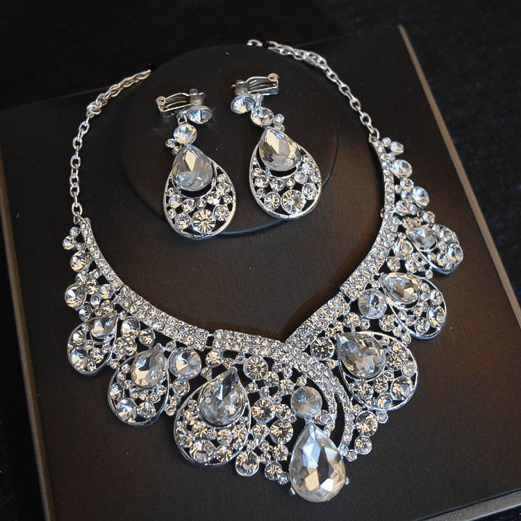 Silver necklace and earrings set on a dark surface