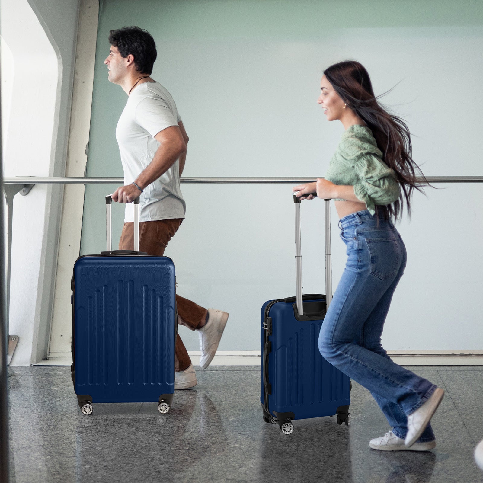 Two people with blue suitcases walking in an airport.