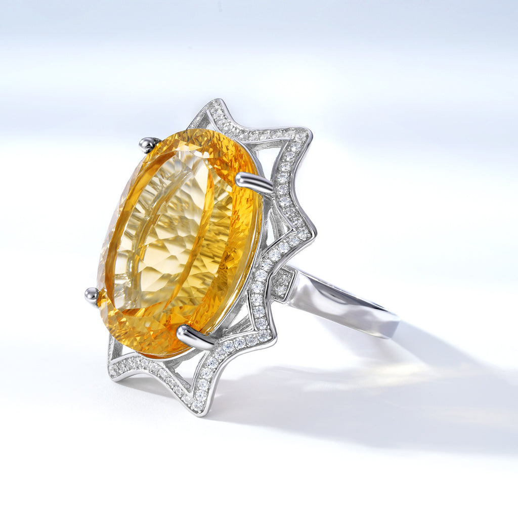 Ring with a large yellow gemstone and silver band on a light background