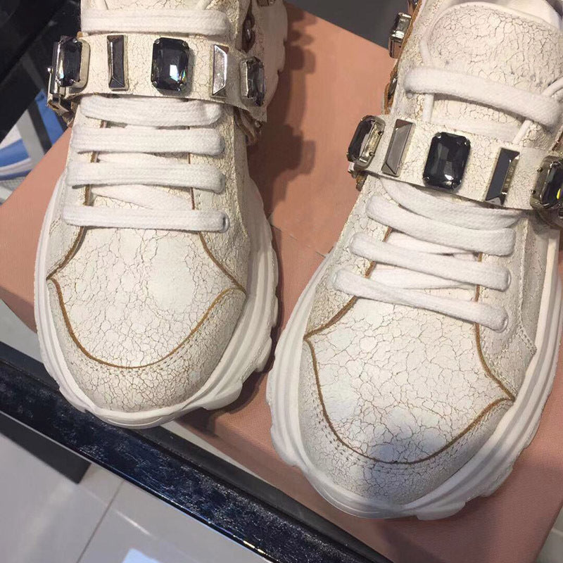 Pair of white sneakers with decorative elements on a surface