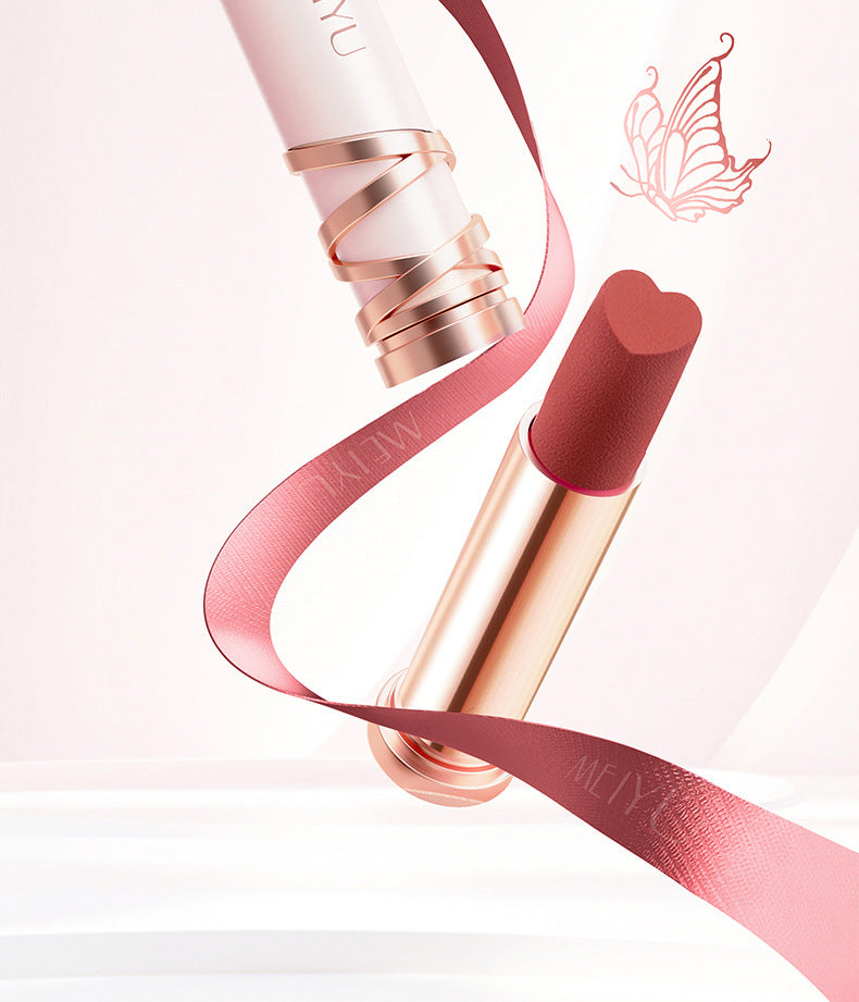 Lipstick with rose gold casing and pink ribbon on a light pink background