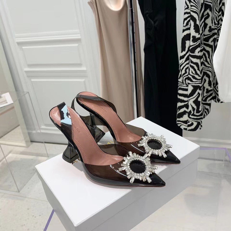 Brown high-heeled shoes with decorative embellishments on a white platform.