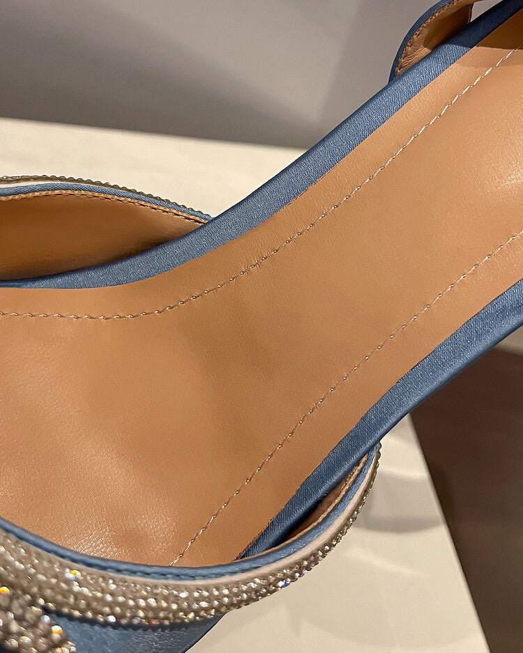 Close-up of a sandal with blue and brown straps on a neutral background
