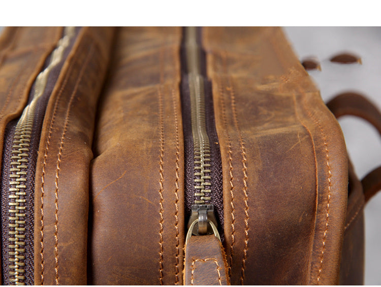 Close-up of a brown leather bag with gold zippers on a white background