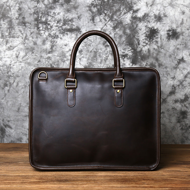 Brown leather briefcase on a wooden surface with a textured gray wall background