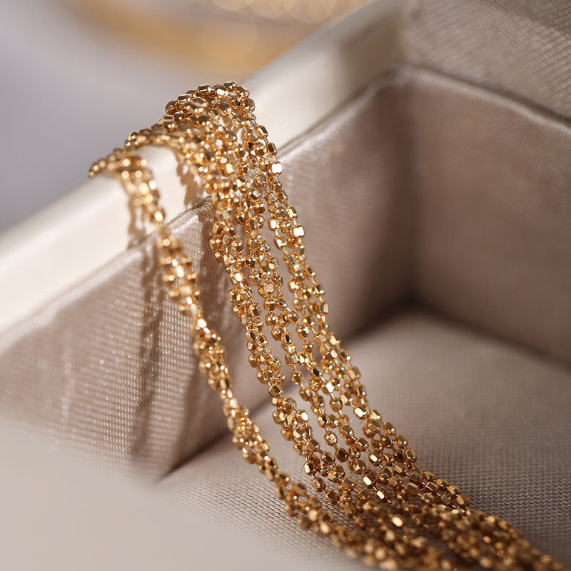 Gold chain necklace on a soft fabric surface