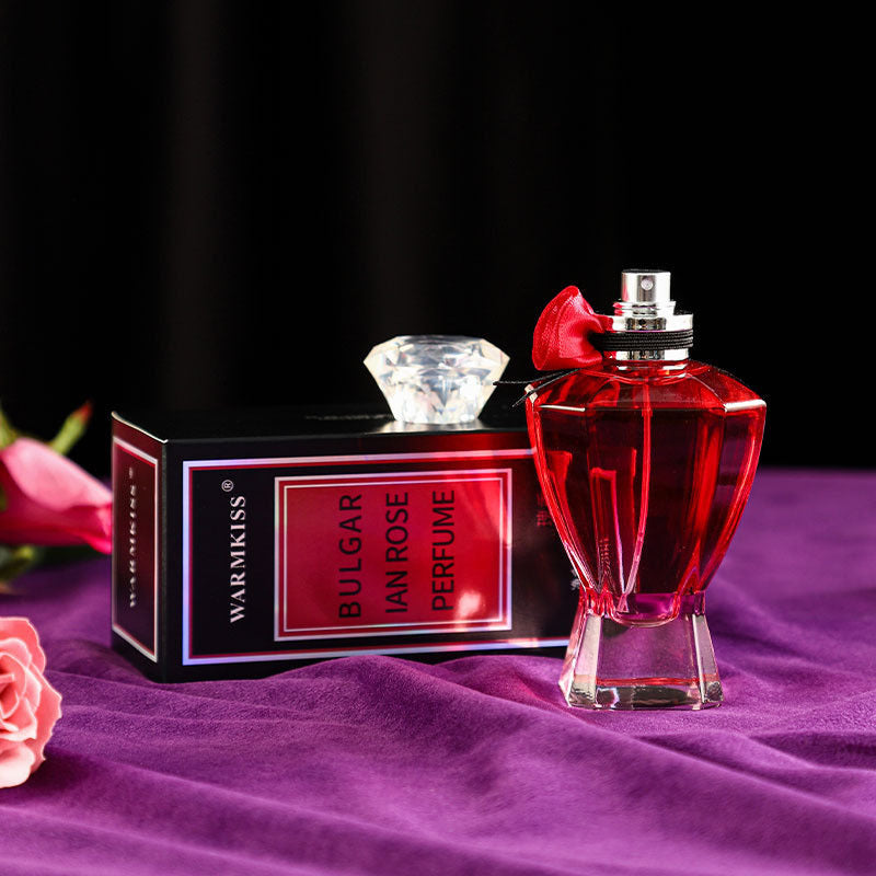 Perfume bottle and packaging with a diamond and pink flowers on a dark background