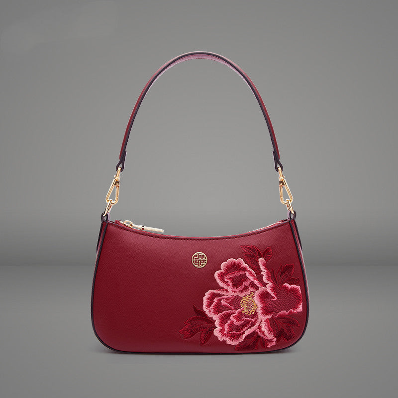 Red handbag with floral embroidery on a gray background