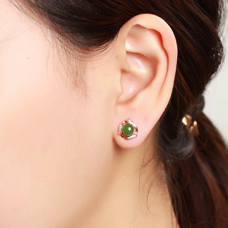 Close-up of an ear wearing a green gemstone earring with a blurred background