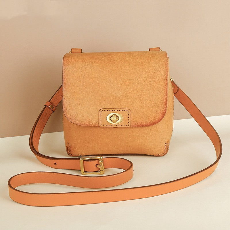 Brown leather crossbody bag with a strap on a beige background